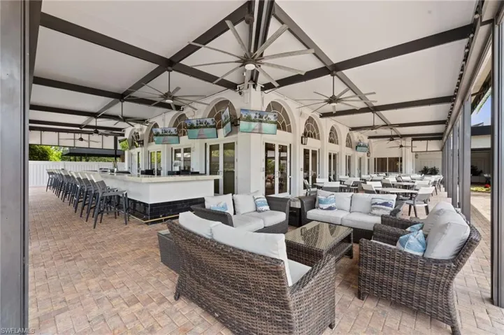 Expansive covered patio featuring brick paver flooring and multiple ceiling fans