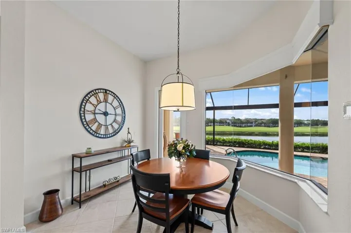 Dining area featuring a bay window, pool, and golf course beyond
