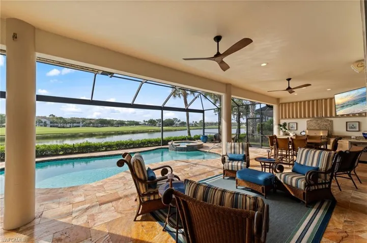 Screened lanai featuring a swimming pool, integrated spa, and travertine tile decking
