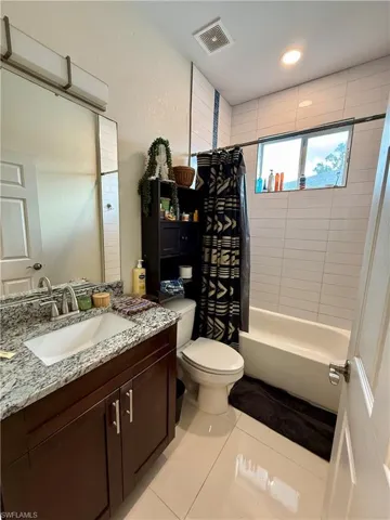 Bathroom featuring light tile patterned floors, shower / bath combo, and vanity