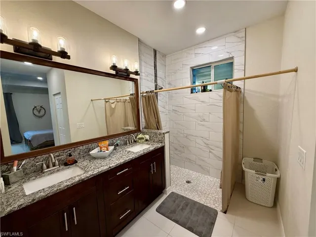Bathroom featuring a stall shower, double vanity, recessed lighting, ensuite bathroom, and light tile patterned flooring