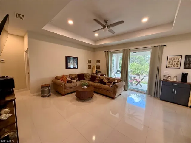 Living room with a ceiling fan, recessed lighting, a tray ceiling, and light tile patterned floors