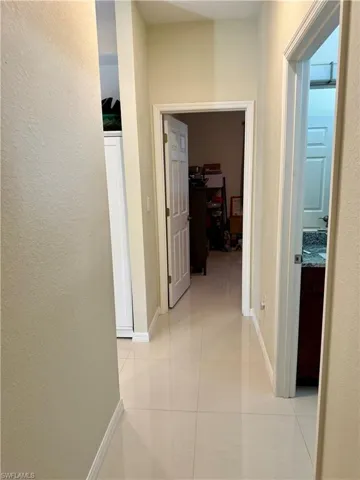 Hallway featuring a textured wall and light tile patterned floors