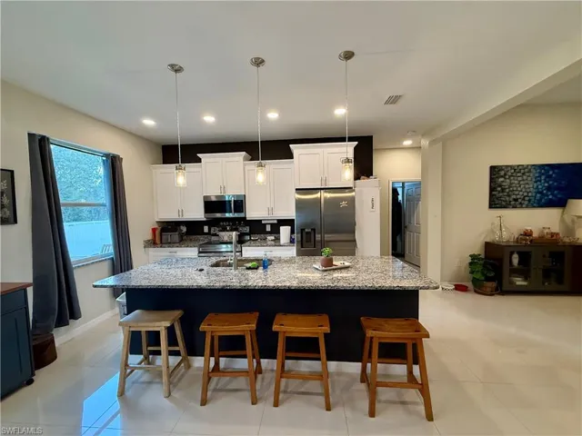 Kitchen featuring a breakfast bar, stainless steel appliances, and light stone countertops