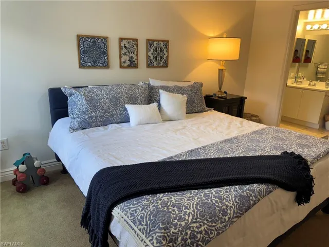 Bedroom featuring light colored carpet and ensuite bath