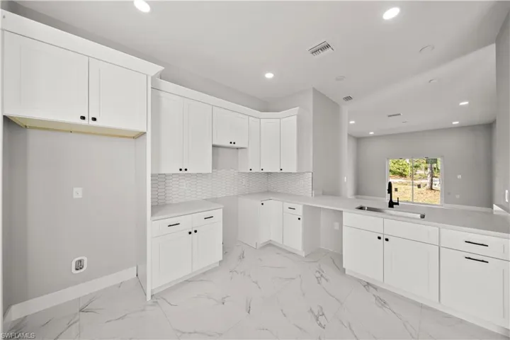 Kitchen featuring backsplash, a sink, recessed lighting, and visible vents