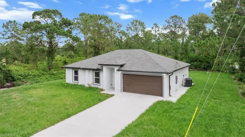 View of front facade featuring a garage, stucco siding, a front yard, concrete driveway, and roof with shingles
