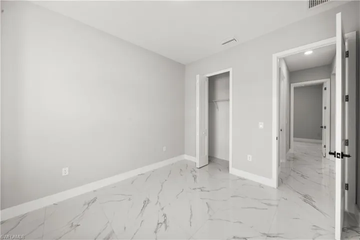 Unfurnished bedroom featuring baseboards, marble finish floor, and visible vents