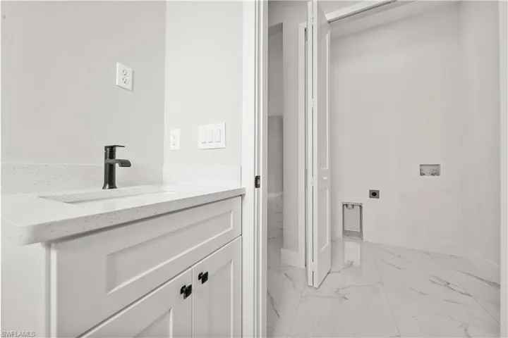 Bathroom with marble finish floor, vanity, and baseboards