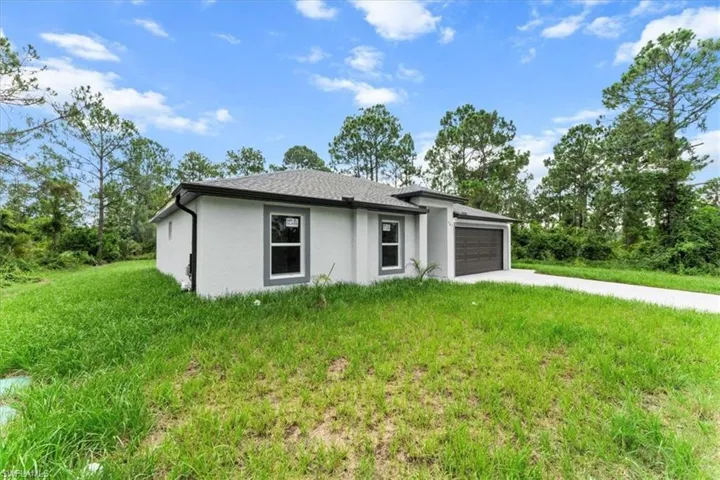 Prairie-style house featuring an attached garage, stucco siding, concrete driveway, and a front lawn