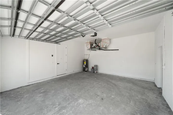 Garage featuring electric water heater and a garage door opener
