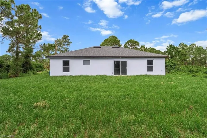Back of house featuring stucco siding and a yard