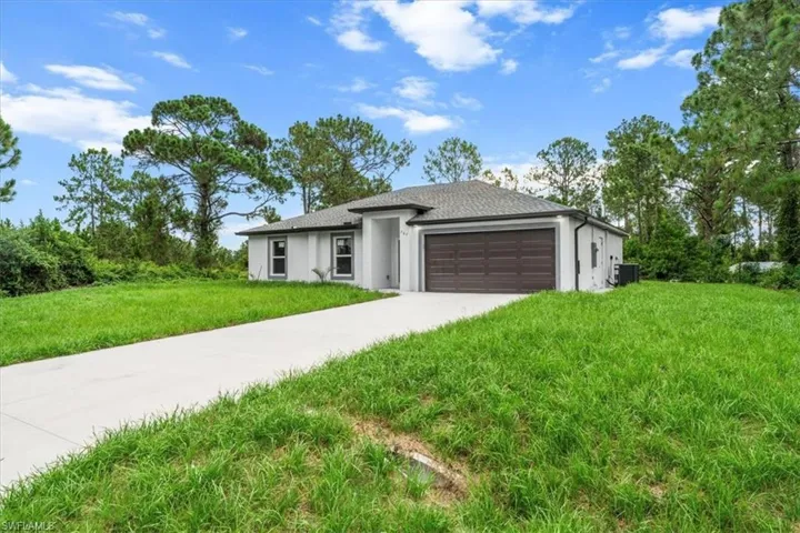 Prairie-style house featuring a garage, driveway, stucco siding, and a front lawn