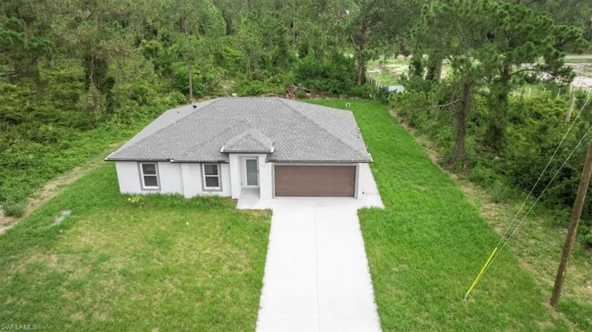 View of front of property featuring a garage, concrete driveway, a front yard, and stucco siding