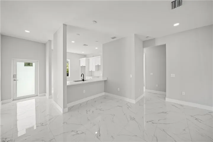 Unfurnished living room with a sink, baseboards, visible vents, and recessed lighting