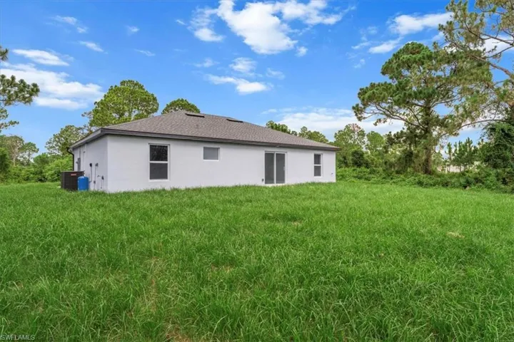 Rear view of property with stucco siding and a lawn