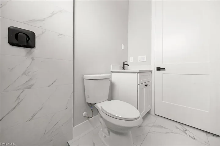 Bathroom featuring marble finish floor, toilet, and vanity