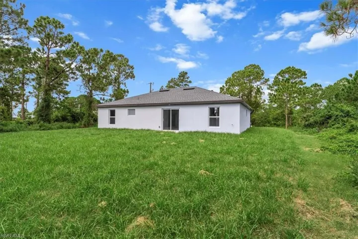 Back of house featuring stucco siding and a lawn