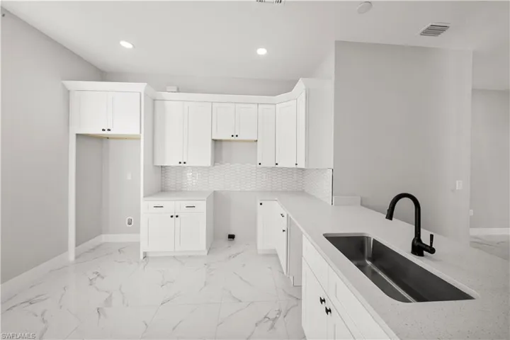 Kitchen with a sink, marble finish floor, visible vents, and tasteful backsplash