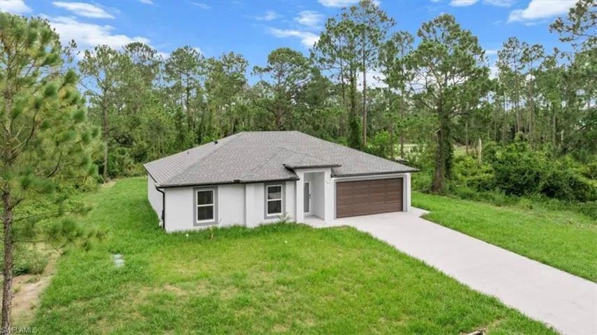 View of front of home featuring concrete driveway, stucco siding, an attached garage, a front lawn, and roof with shingles