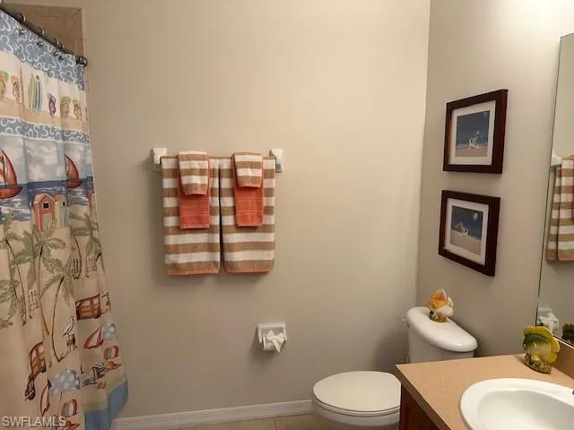 Bathroom with vanity, curtained shower, and toilet