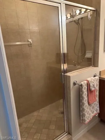Bathroom with tile patterned flooring, vanity, and a shower with door