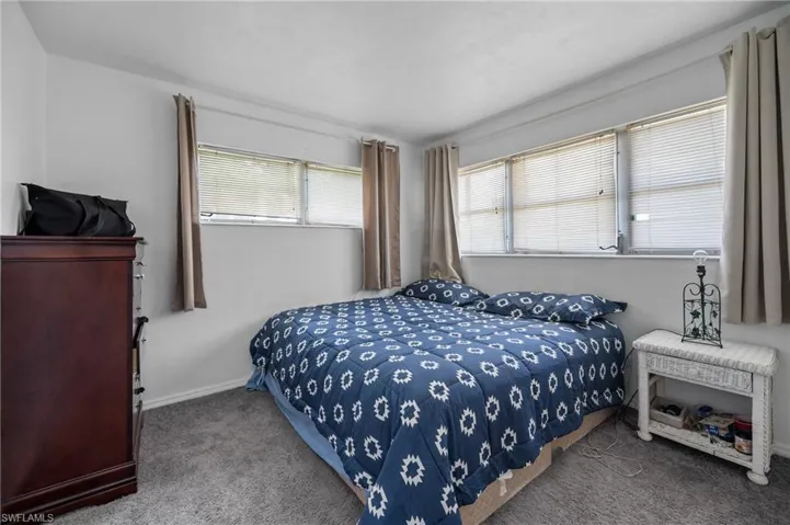 Carpeted room with a ceiling fan, two windows featuring horizontal blinds, and neutral wall tones