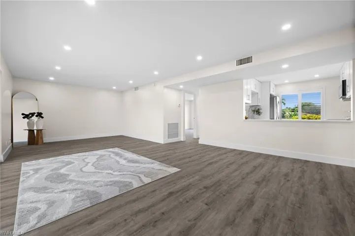 Unfurnished living room featuring dark wood-style floors and recessed lighting