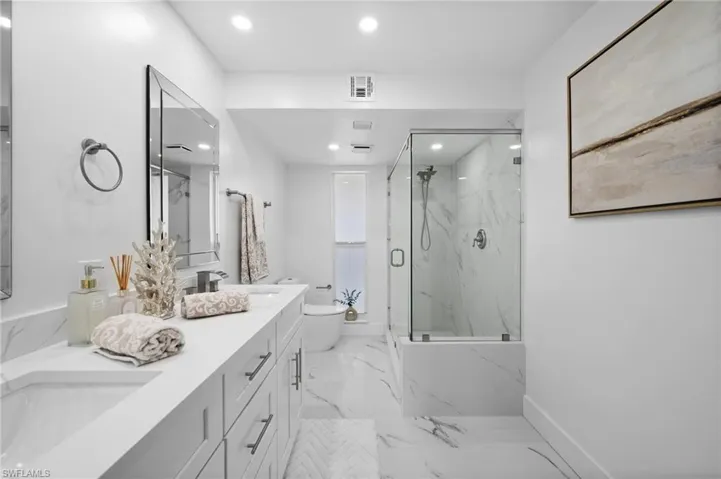 Full bathroom with a marble finish shower, double vanity, recessed lighting, and light marble finish floors
