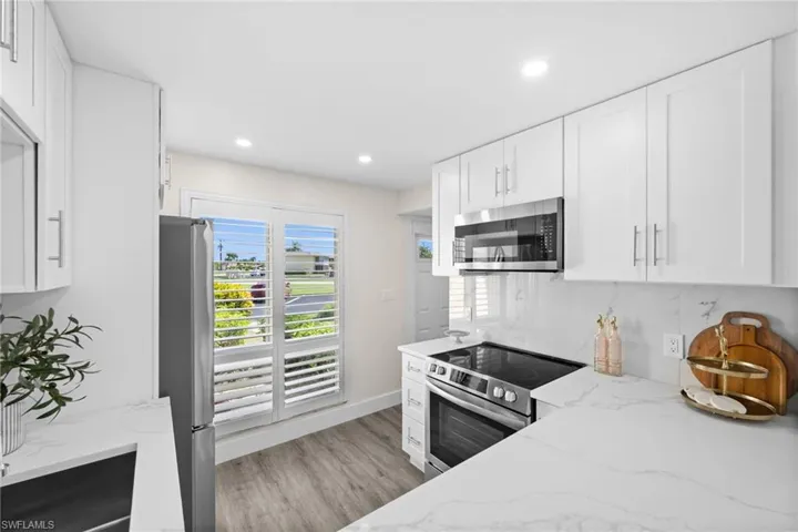 Kitchen featuring light stone counters, white cabinets, stainless steel appliances, and recessed lighting