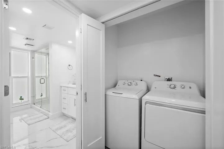 Washroom with light marble finish flooring, washer and clothes dryer, and recessed lighting