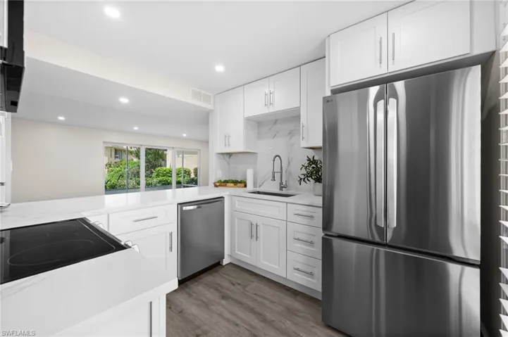 Kitchen with white cabinetry, stainless steel appliances, recessed lighting, light wood-style flooring, and light stone counters