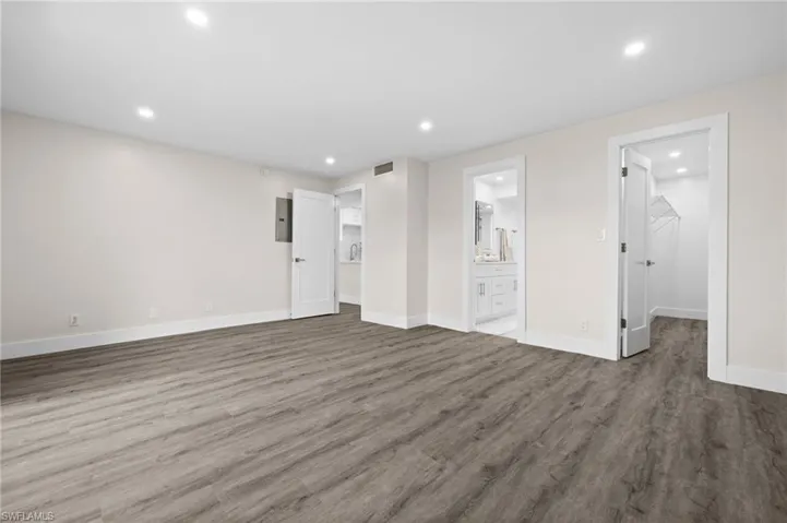 Unfurnished bedroom featuring recessed lighting, dark wood finished floors, a spacious closet, connected bathroom, and electric panel