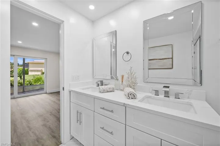 Bathroom with double vanity, recessed lighting, and light wood finished floors