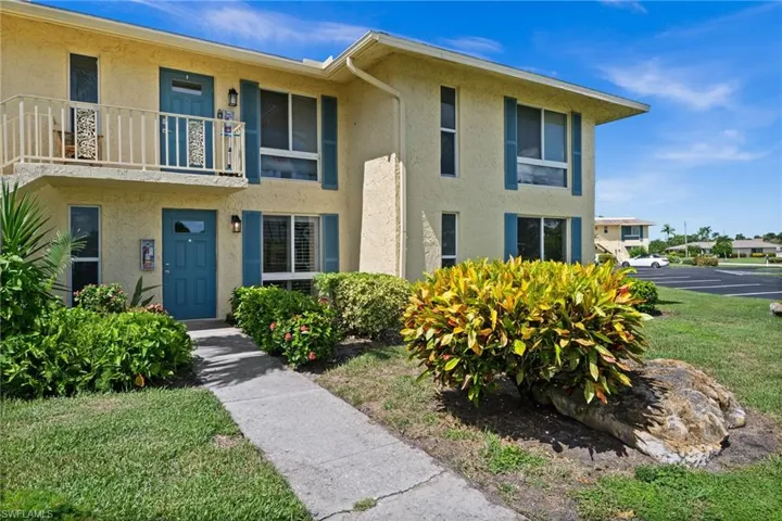 View of front of home with a balcony, stucco siding, and a front lawn
