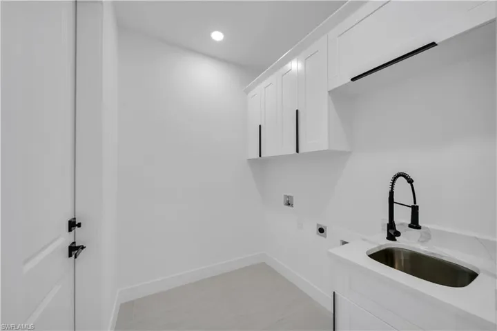 Laundry area featuring hookup for a washing machine, baseboards, a sink, hookup for an electric dryer, and cabinet space