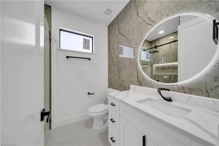 Bathroom featuring visible vents, baseboards, toilet, vanity, and an enclosed shower