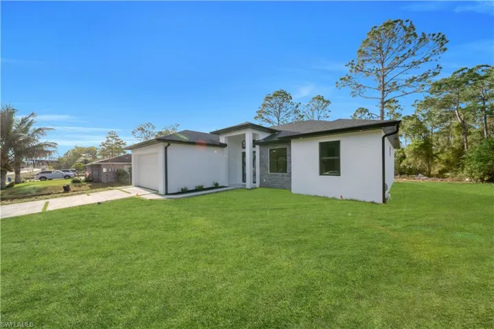 View of front facade with stucco siding, driveway, a front lawn, and an attached garage