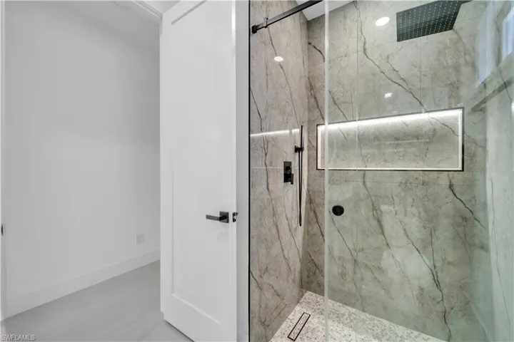 Bathroom featuring baseboards and a marble finish shower