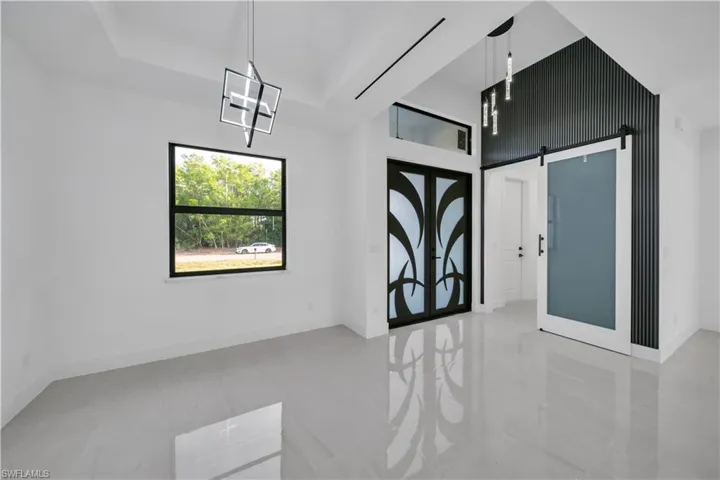 Unfurnished room with a notable chandelier, baseboards, a barn door, and a tray ceiling