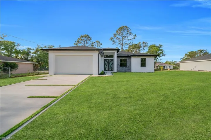 View of front facade with fence, an attached garage, stucco siding, a front yard, and driveway