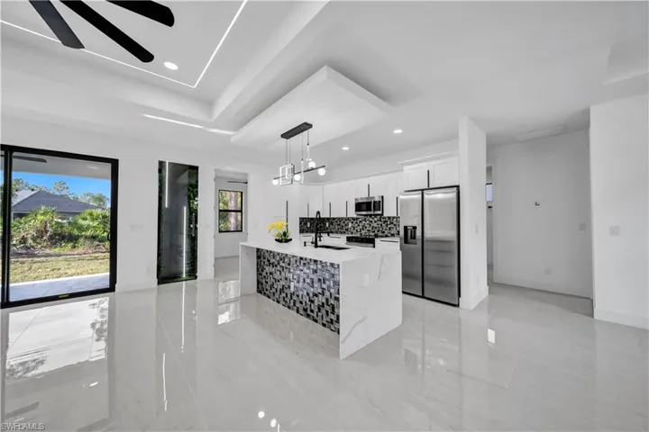 Kitchen featuring an island with sink, a sink, white cabinetry, tasteful backsplash, and stainless steel appliances