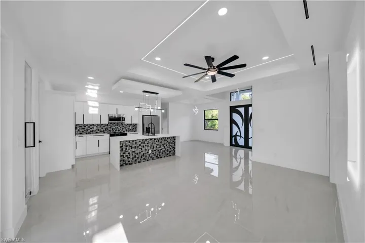 Living area featuring recessed lighting, a tray ceiling, baseboards, and ceiling fan