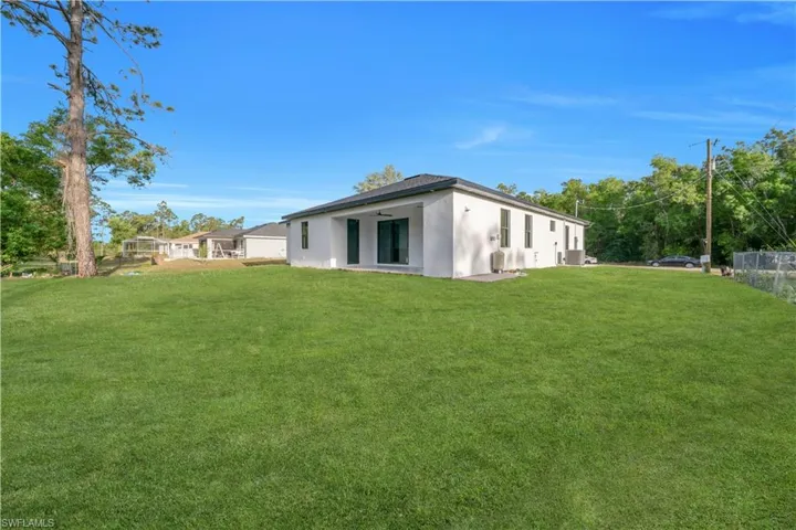 Back of property featuring stucco siding, fence, and a yard