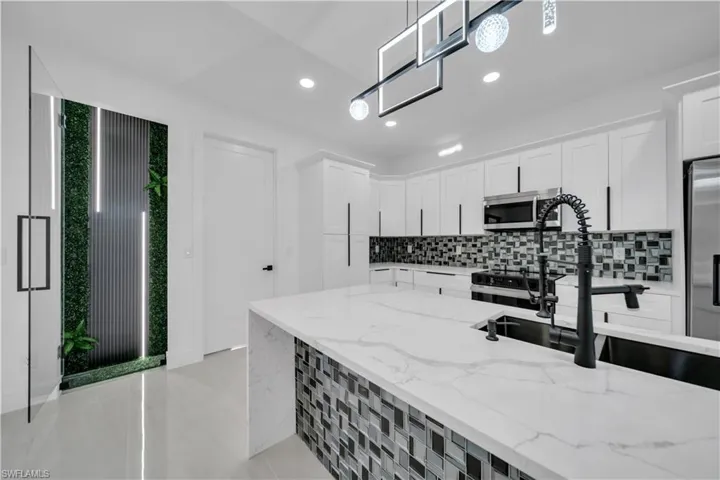 Kitchen featuring white cabinets, tasteful backsplash, light stone countertops, and stainless steel appliances