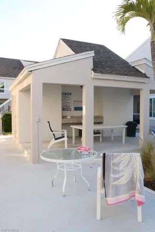 Covered outdoor structure featuring a shingled roof and stucco exterior