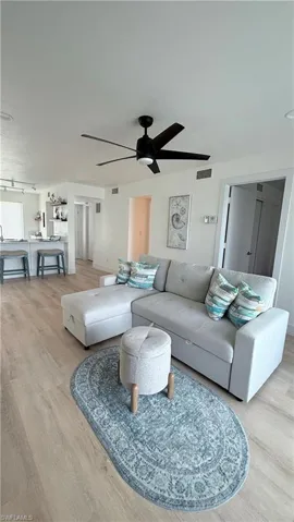 Open-concept living space with light wood-finish flooring, a contemporary black ceiling fan with five blades, and recessed lighting
