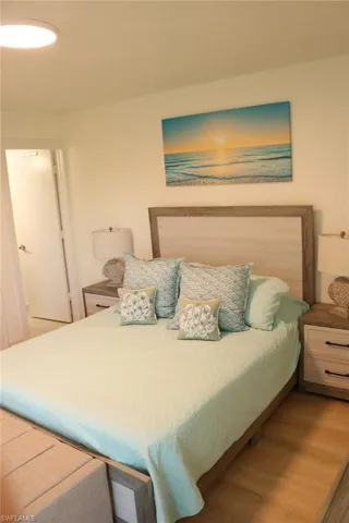 Spacious bedroom featuring wood-finish flooring, a light wood-tone headboard, and dual nightstands with drawer storage