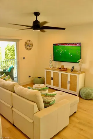 Living area featuring wood-finish flooring, a contemporary ceiling fan with integrated lighting, and a sliding glass door leading to an outdoor space