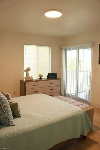 Spacious room featuring wood-finish flooring, a contemporary flush-mount ceiling light, and a window with horizontal blinds